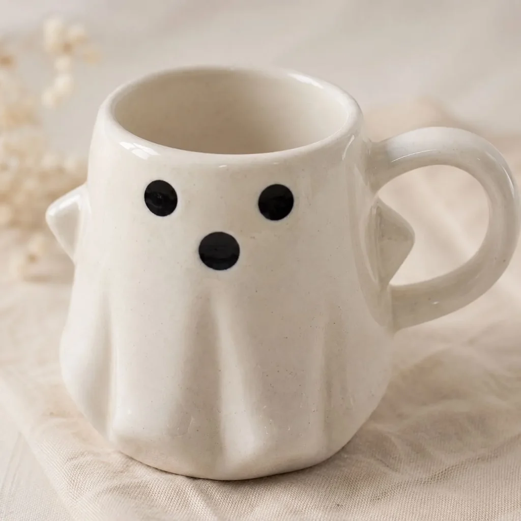 Off-White Ghost Face Ceramic Mug with Black Eyes styled in a home setting